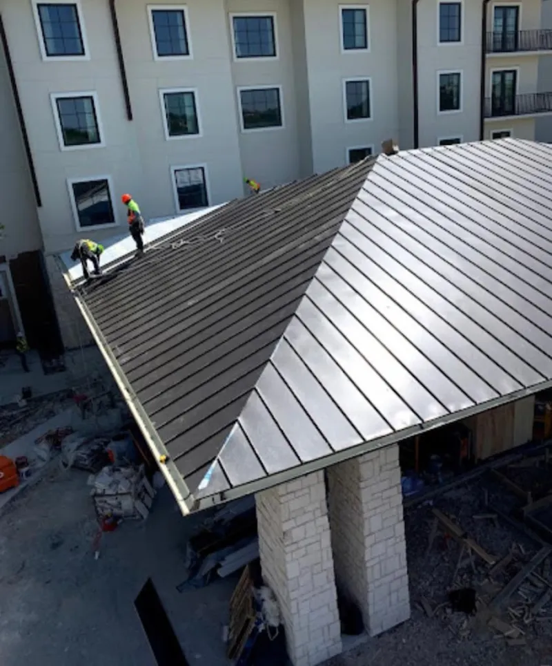 Crew installing standing seam metal roof panels on a commercial project in Kaysville